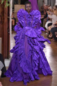 a model wears a brilliant purple gown on the runway