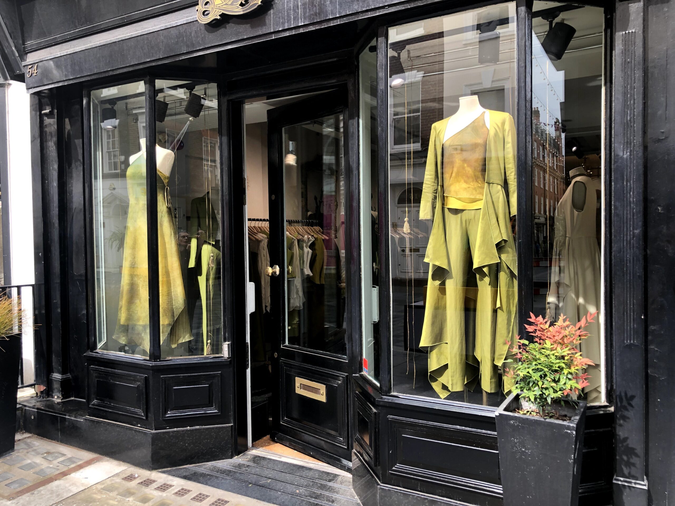 A shop window in London, with a chartreuse outfit in the window - a combination of Pantone's Spring/Summer 2023 fashion colors Blazing Yellow and Titanite.