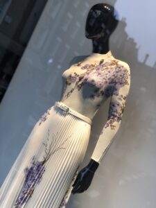 A photo of a London storefront taken by Color  Expert Leatrice Eiseman, showing a black mannequin in an an ivory pleated dress with purple flowers on it.