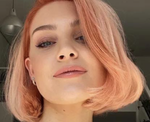 A young woman with peach-colored hair in a bob, the color of Pantone's new color of the year, Peach fuzz