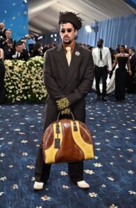 Rapper Bad Bunny wears a brown suit at the Met Gala and carries a large bag