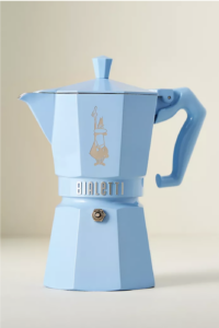 A sky blue bialetti espresso maker against a neutral tan ground