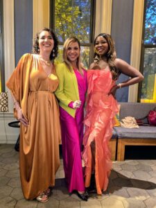 Three attendees of the Association of Image Consultants International conference in Chicago 2026 pose in bright colored gowns